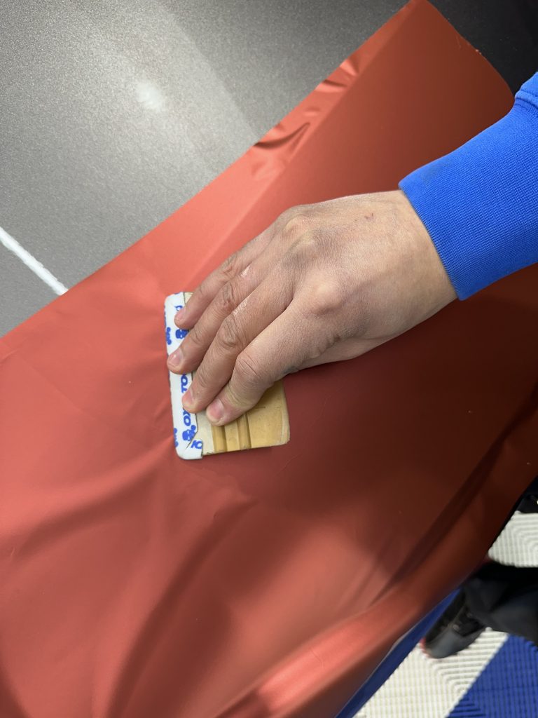 Lissage d'un film covering rouge à la raclette – pourquoi choisir un polymère pour vos événements