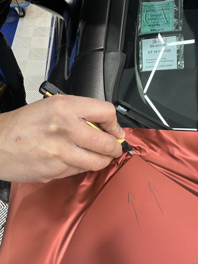 Découpe d'un film covering rouge au niveau d'une vitre – combiner covering, PPF et film solaire pour une activité