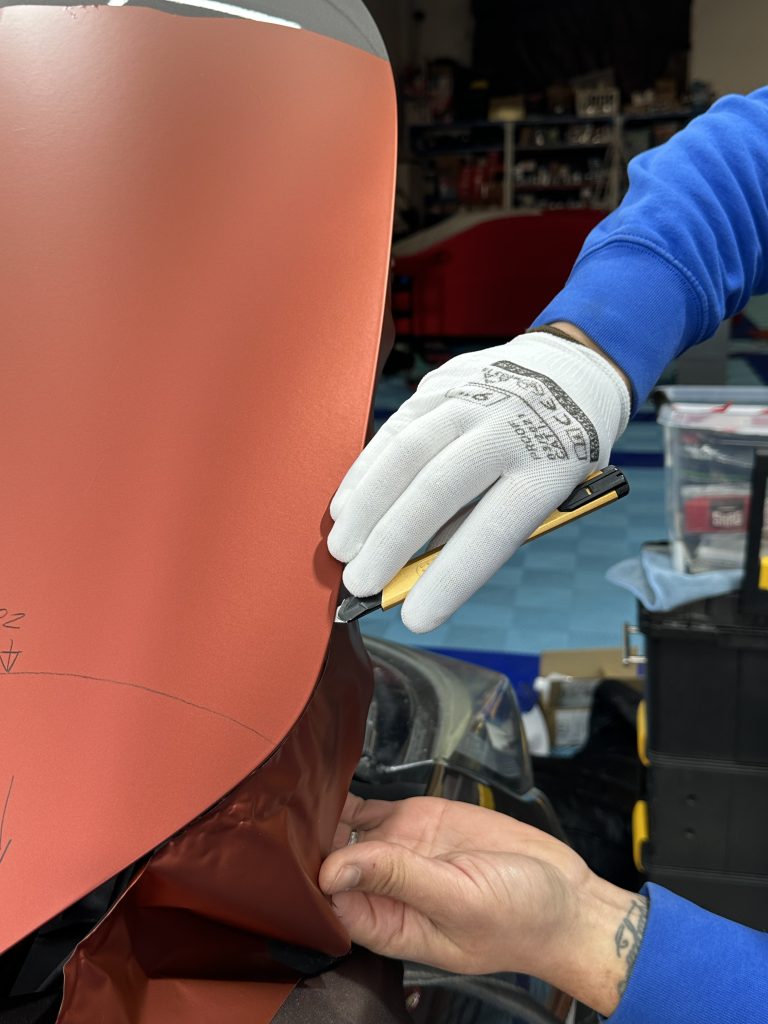 Pose d'un film covering rouge avec gants – reconversion film automobile
