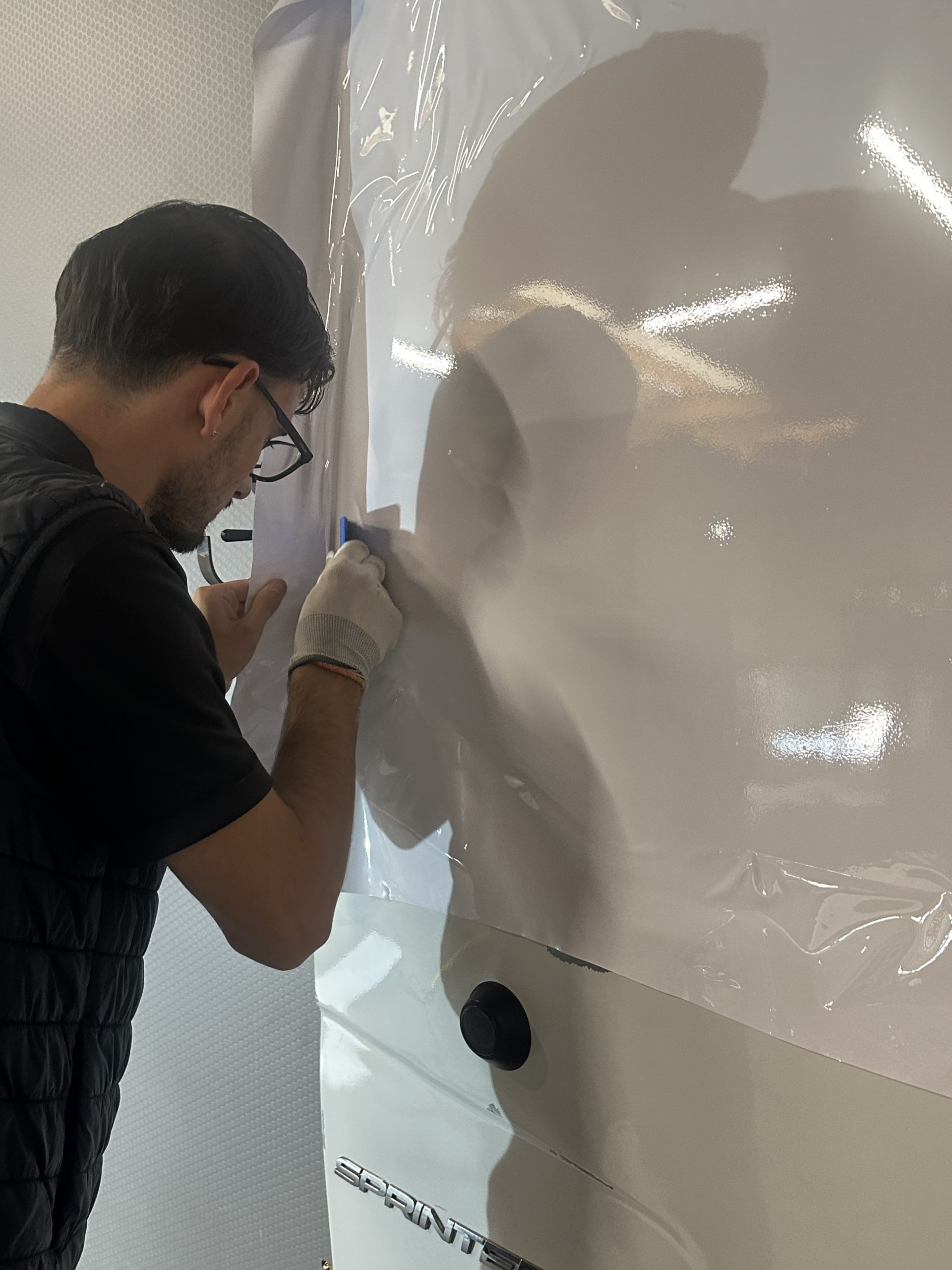 Stagiaire posant un film covering blanc sur une portière – compétences clés pour réussir dans la pose de covering auto