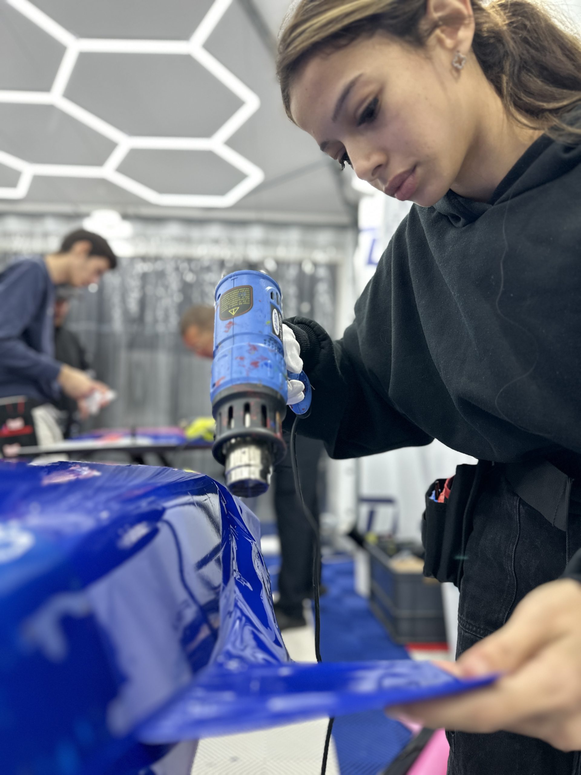 Stagiaire chauffant un film covering bleu au décapeur thermique – covering ou peinture voiture 2025