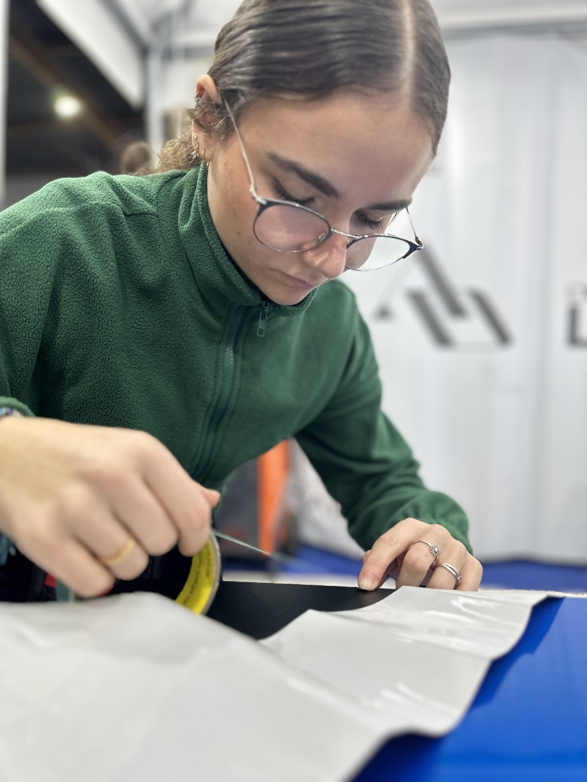 Stagiaire découpant un film covering sur une pièce bleue – évolution salariale 2025 entre débutants et experts en