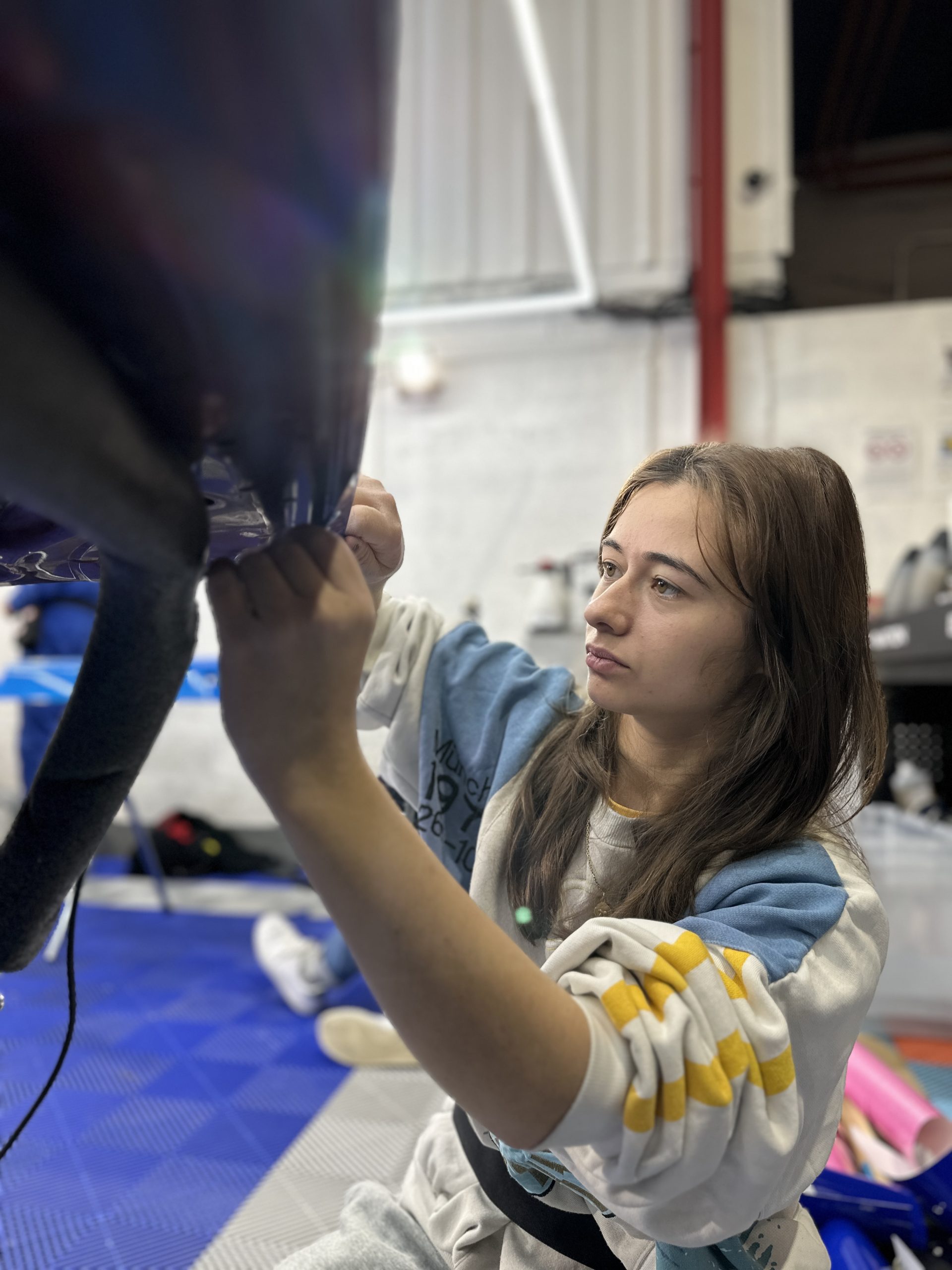 Stagiaire posant un film covering sous un capot relevé – combien facturer pour une pose de covering quand on débute