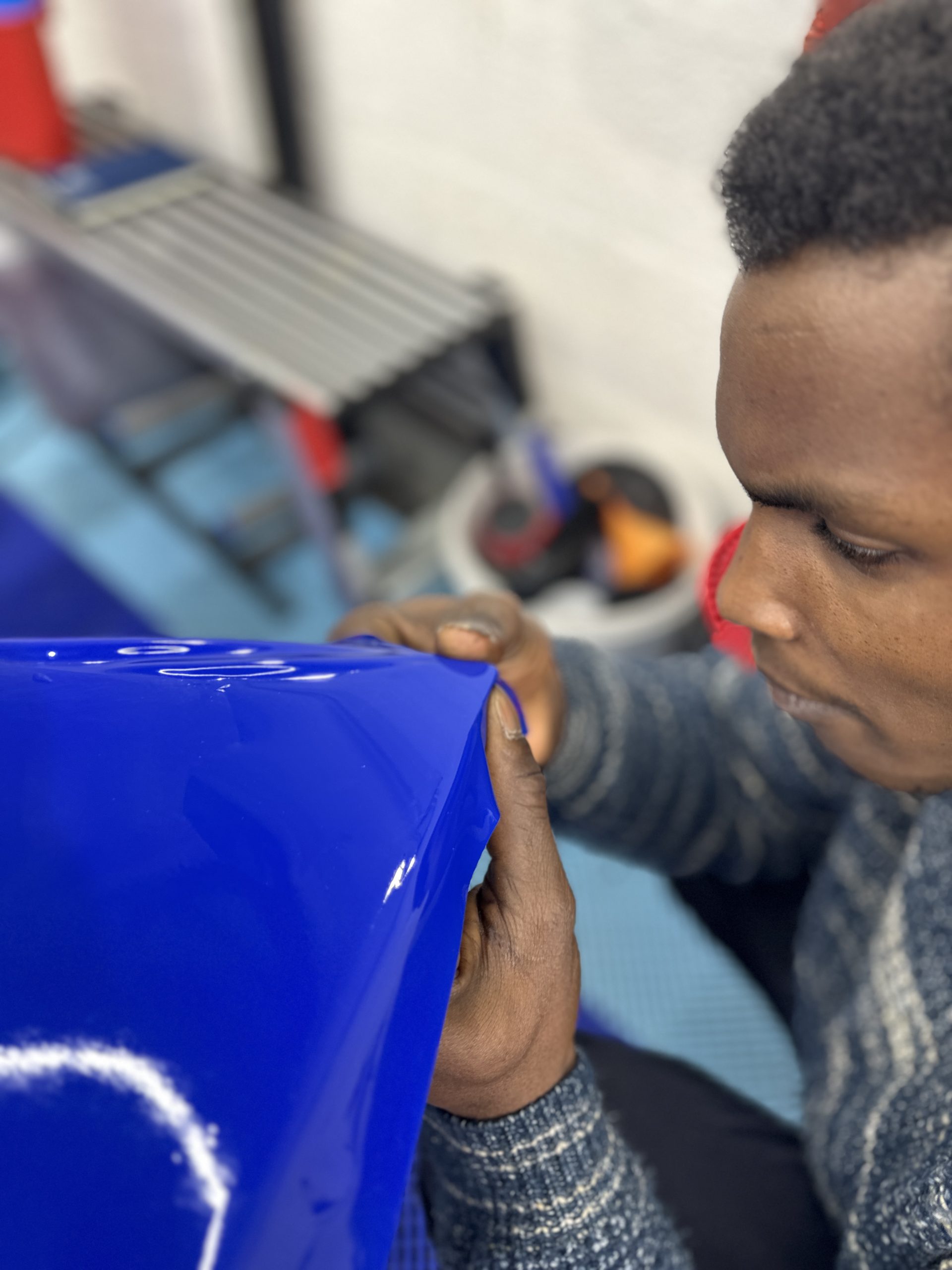 Stagiaire lissant un film covering bleu – comment devenir poseur de covering professionnel en France
