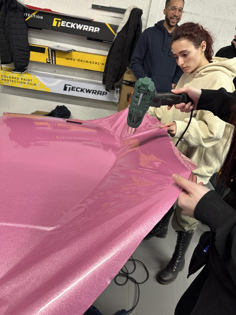Stagiaires posant un film vinyle rose avec un décapeur thermique – combien Coûte Le film covering De Voiture