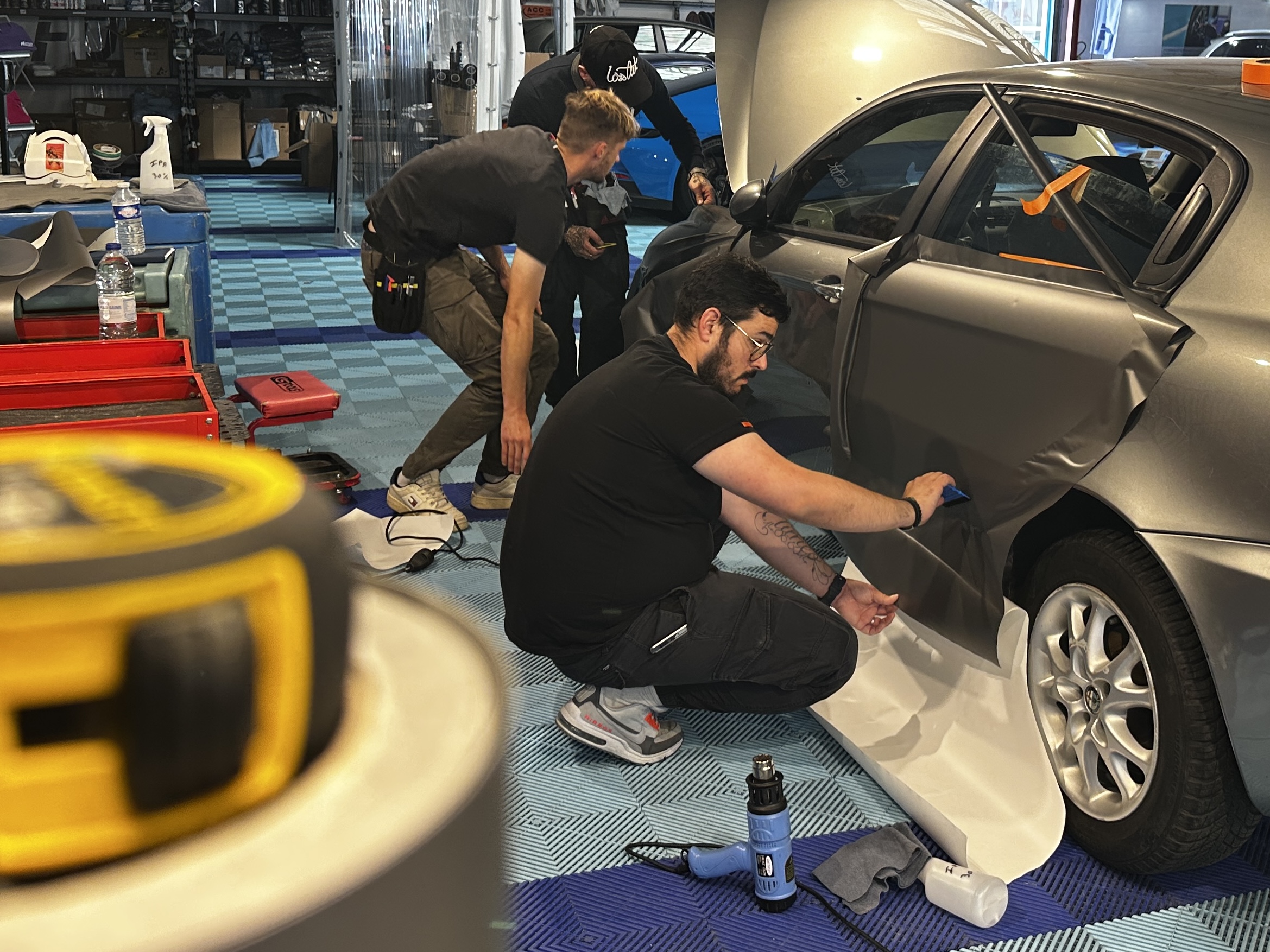 Stagiaires posant un covering sur la portière d'une voiture – quel covering choisir