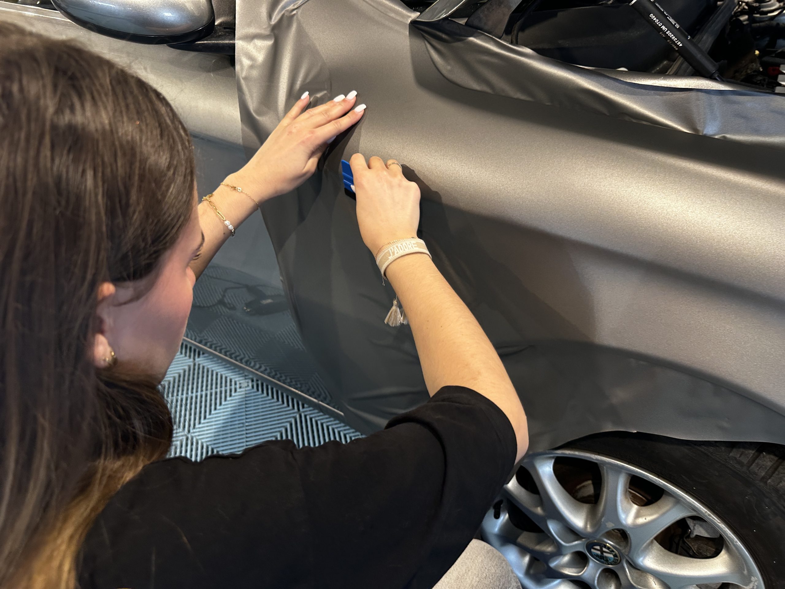 Stagiaire lissant un film covering gris sur une aile avant – quel film covering choisir