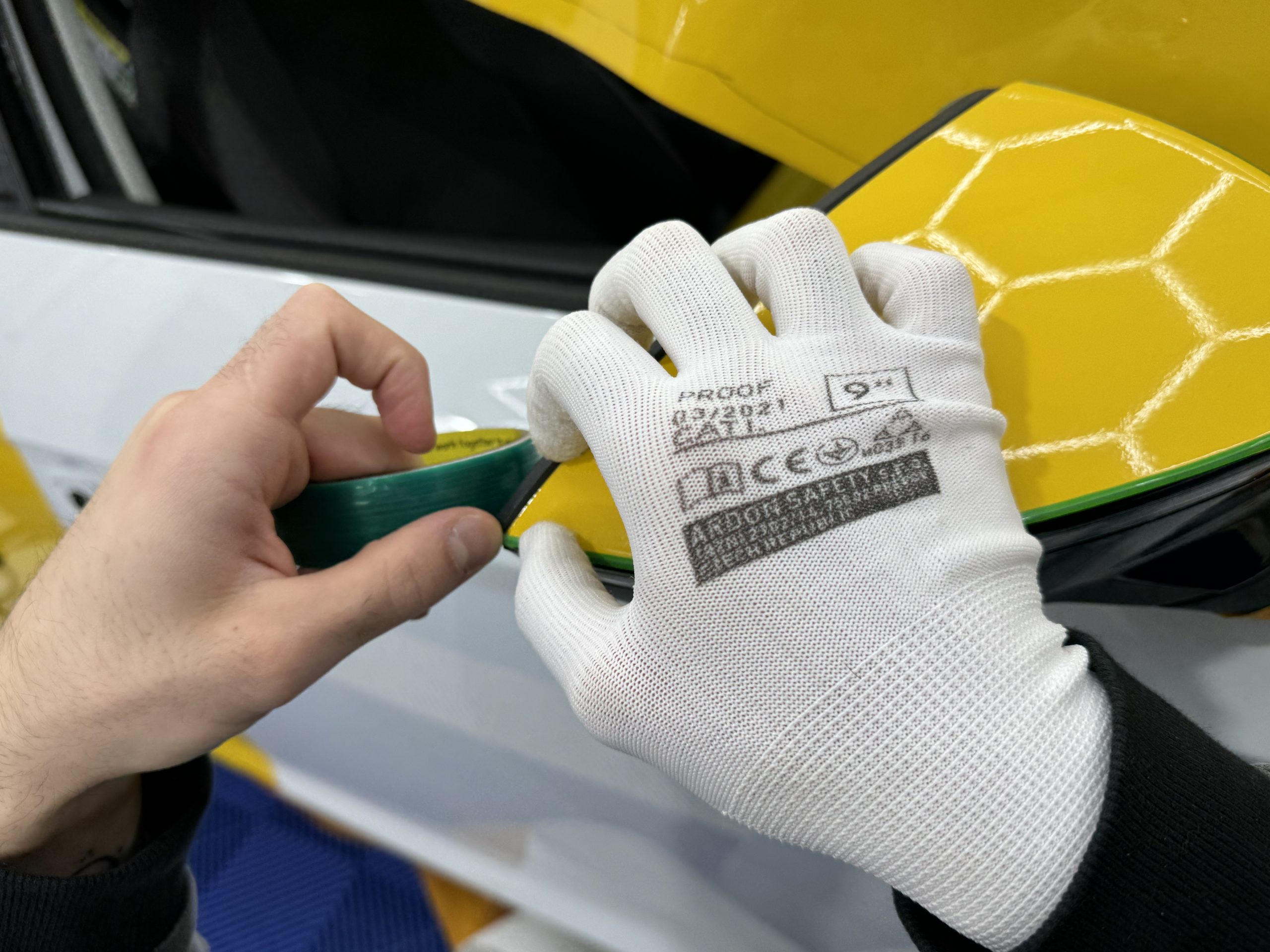Gants de pose et raclette sur un film covering jaune – comment réussir son covering de voiture soi-même