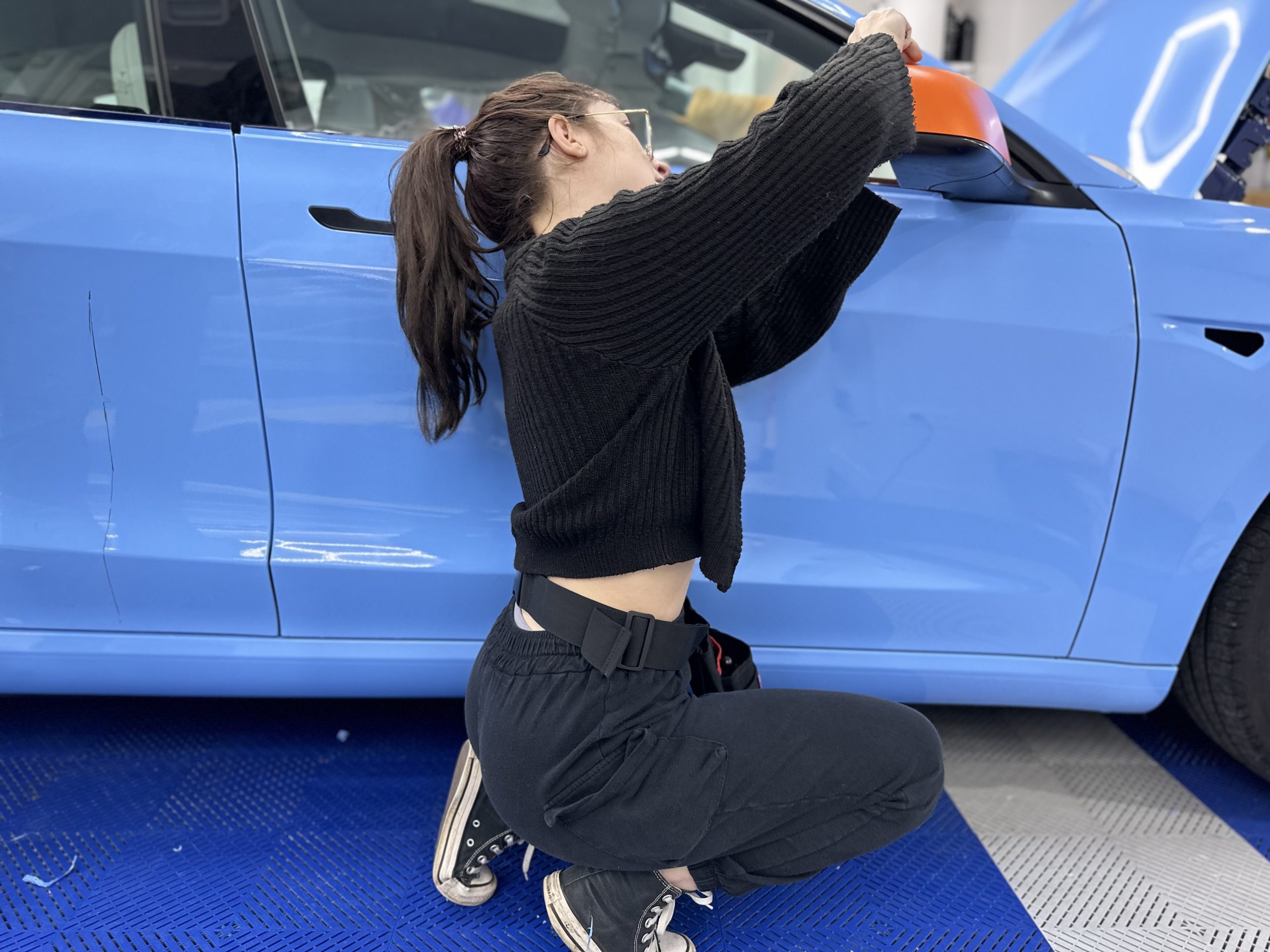Stagiaire posant un film covering sur une voiture bleu ciel – quelle est la durée de vie d’un wrapping automobile