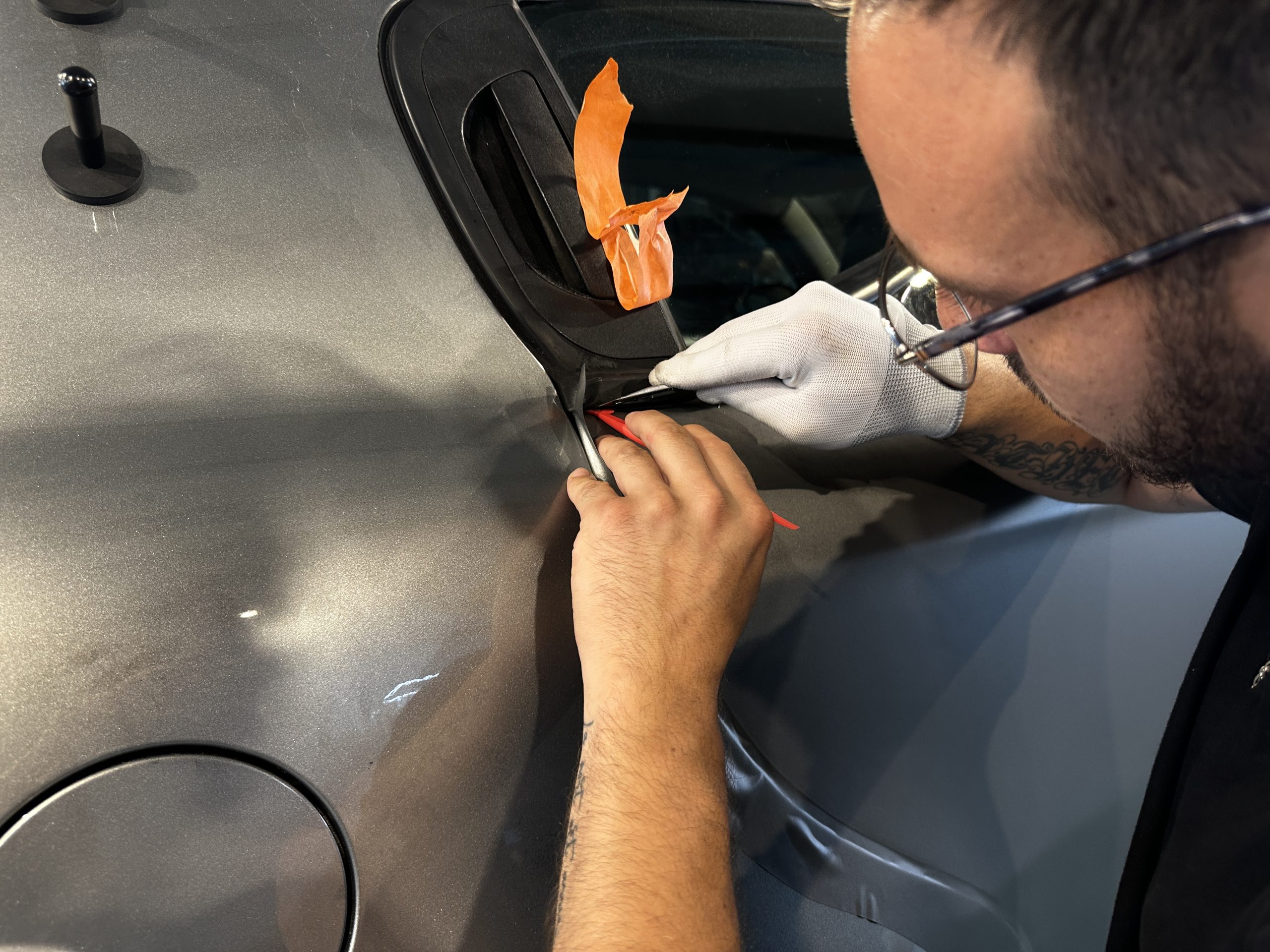Formateur réalisant les finitions d'un covering autour d'une trappe à carburant – formation complète aux métiers du film automobile